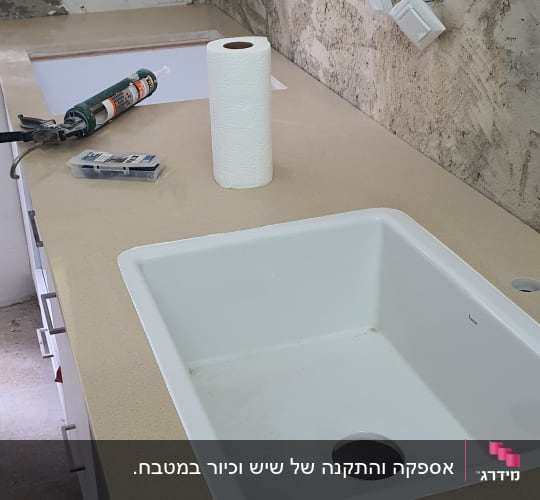 כיור לבן מותקן על משטח שיש במטבח